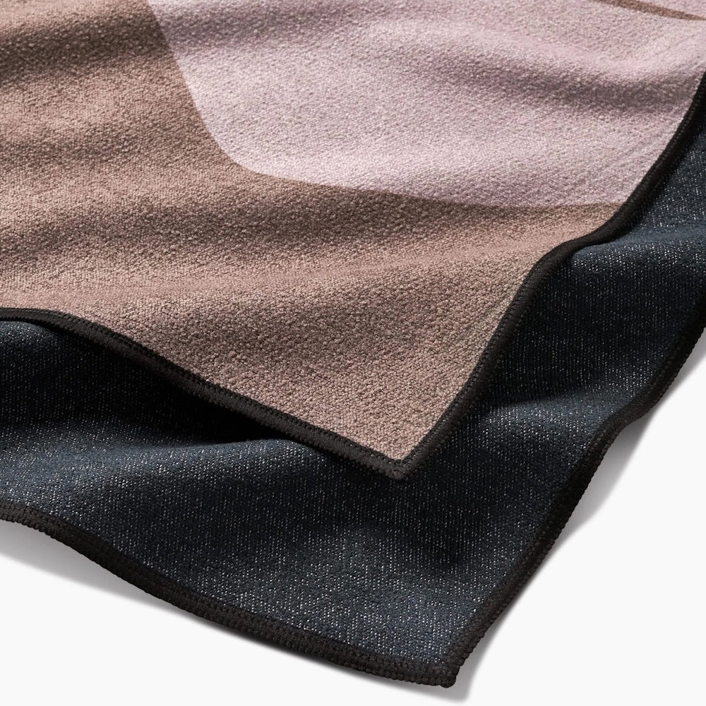 Close-up of a textured towel with a brown and pink pattern on top and a dark gray reverse side.