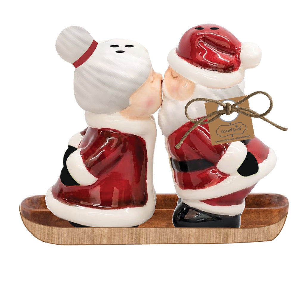 Side view of a red and white ceramic Mr and Mrs Claus salt and pepper shaker set with a branded tag on a wooden base.