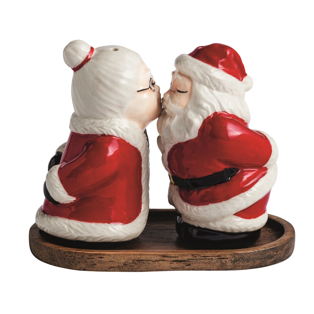 Side view of a red and white ceramic Mr and Mrs Claus salt and pepper shaker set on a wooden base.