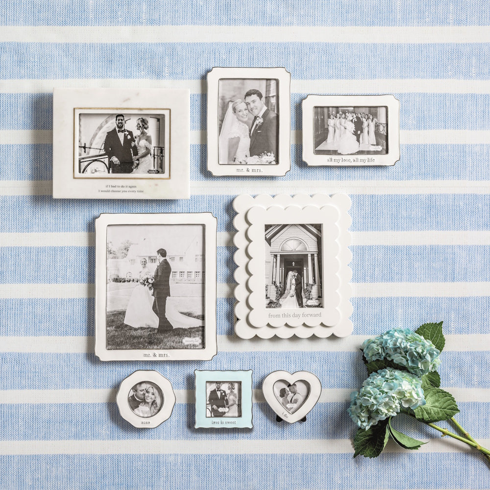 A collection of eight white and cream wedding photo frames of various shapes and sizes on a blue striped background.