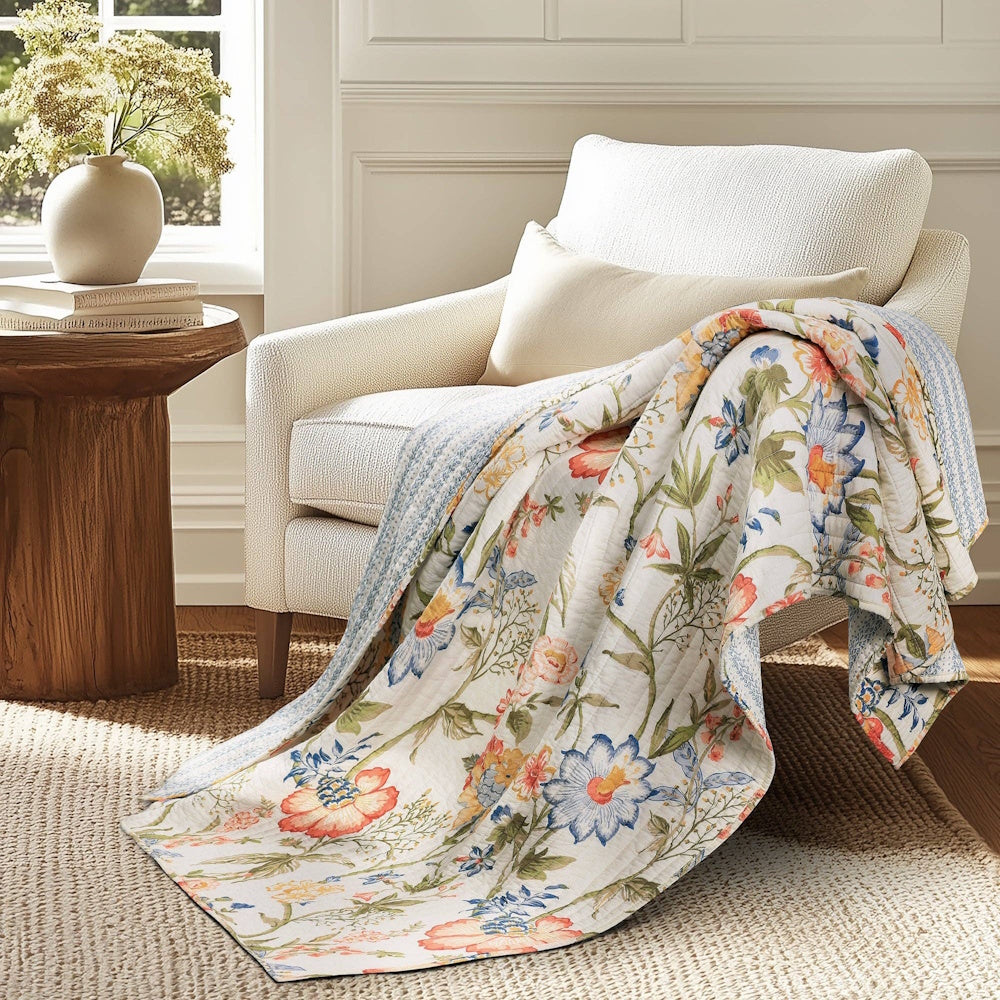 Floral quilted throw blanket draped over a white armchair in a bright, cozy living room.