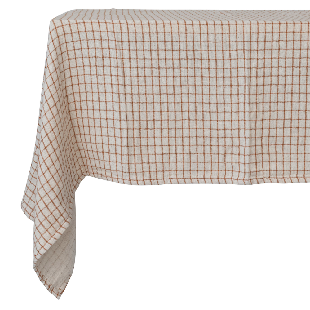 Cream cotton tablecloth featuring a rust-orange grid pattern draped over a table.