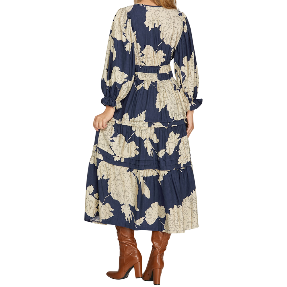 Woman from back in a navy 3/4 sleeve tiered floral midi dress paired with brown leather knee-high boots.