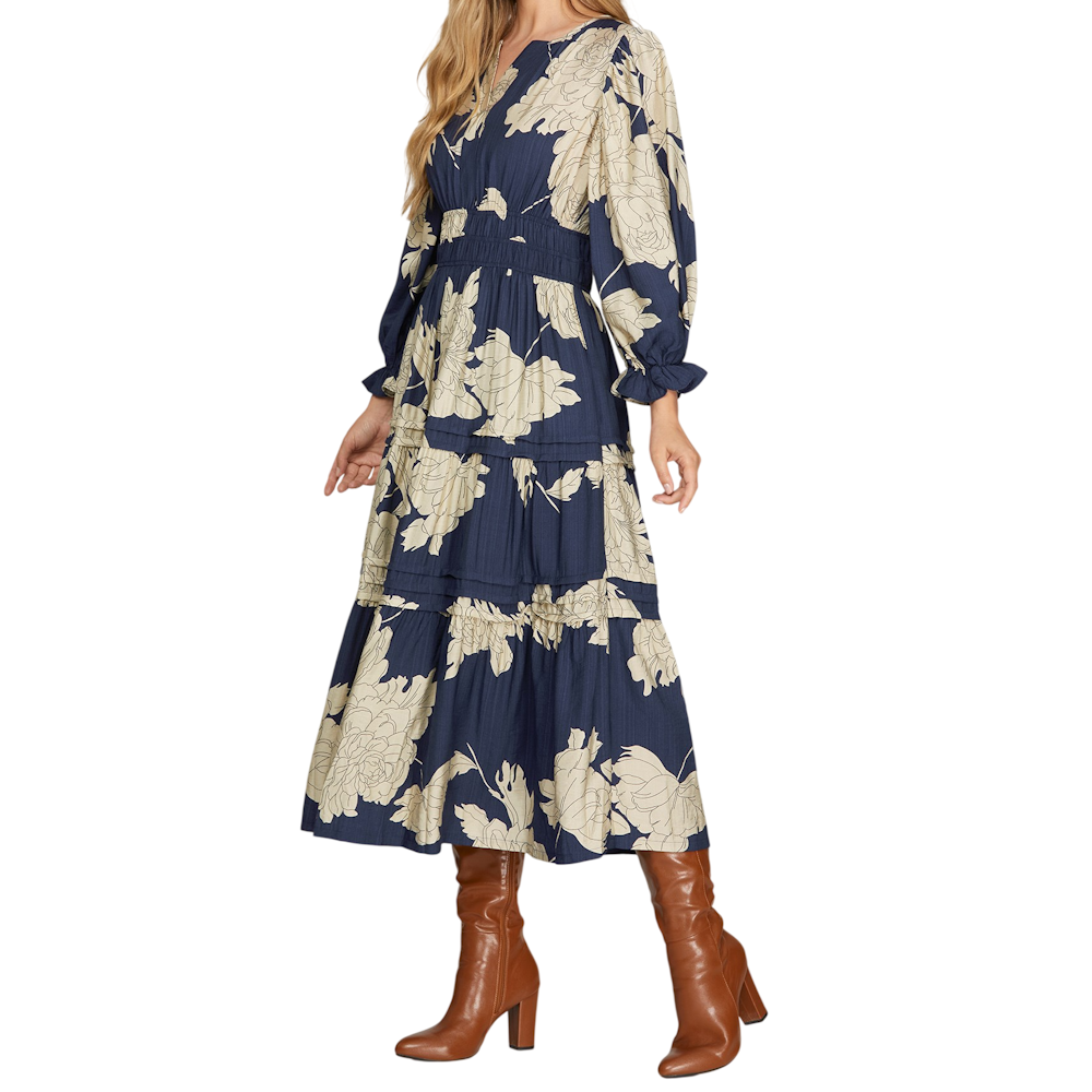 Woman wearing a navy and cream floral tiered midi dress with 3/4 sleeves and brown leather boots.