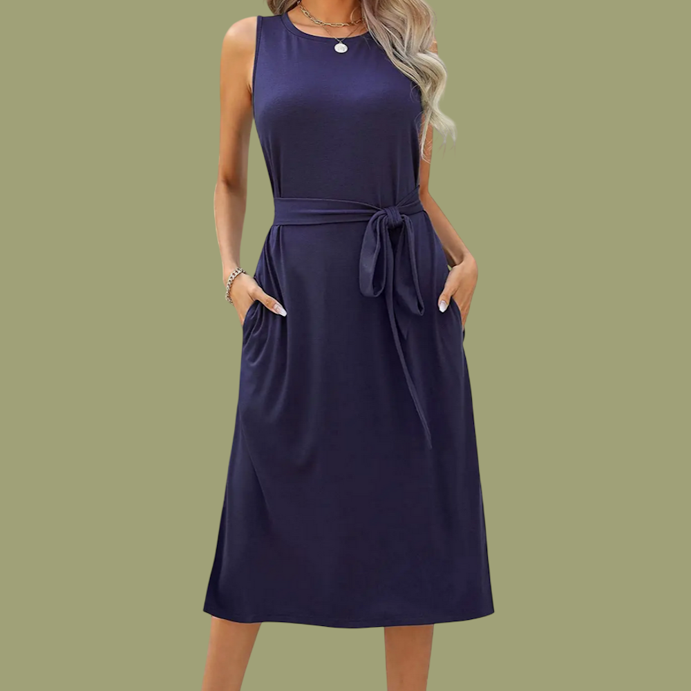 A model wears a navy blue sleeveless midi dress with a tied waist belt and side pockets against an olive backdrop.