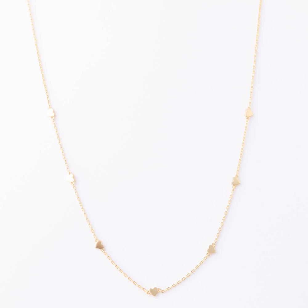 Gold station necklace with tiny heart charms spaced along a delicate chain against a white background.