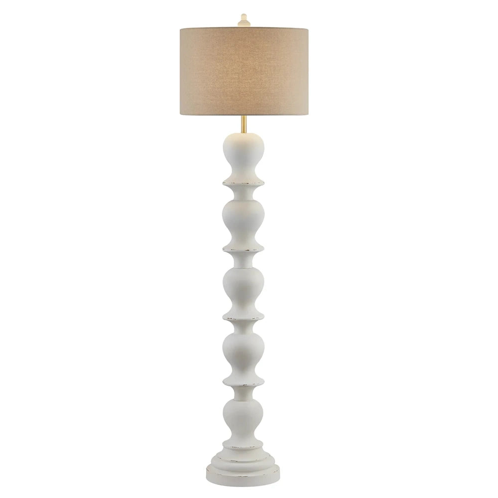 White distressed floor lamp with sculpted turned wood style base, brass accents and beige drum shade.