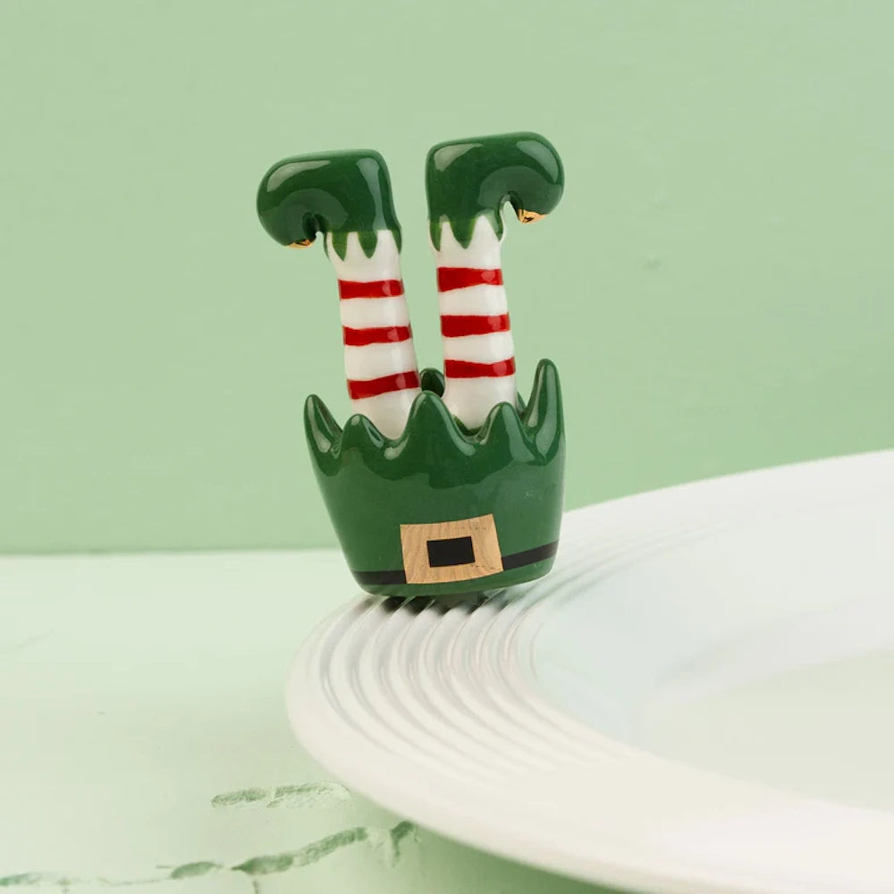 Ceramic elf legs platter decoration with striped socks attached to the rim of a white plate.