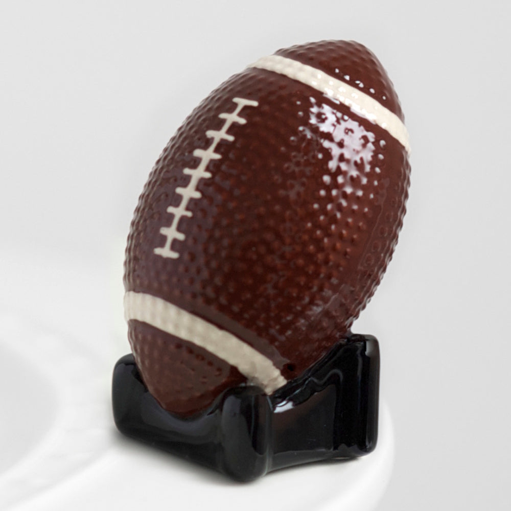 A glossy ceramic football figurine with white laces and stripes, resting on a small black base.
