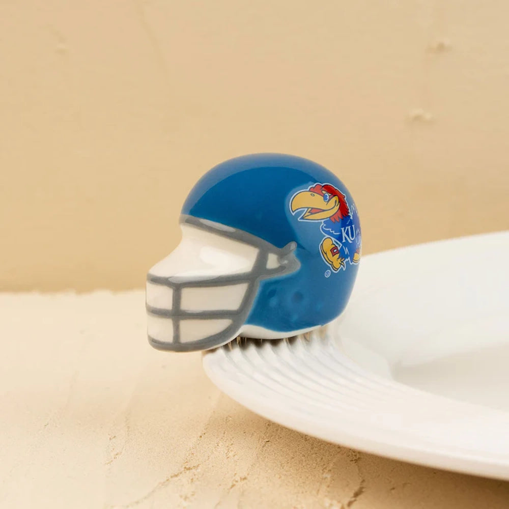 A miniature blue ceramic football helmet featuring the Kansas Jayhawks logo, attached to a white plate rim.