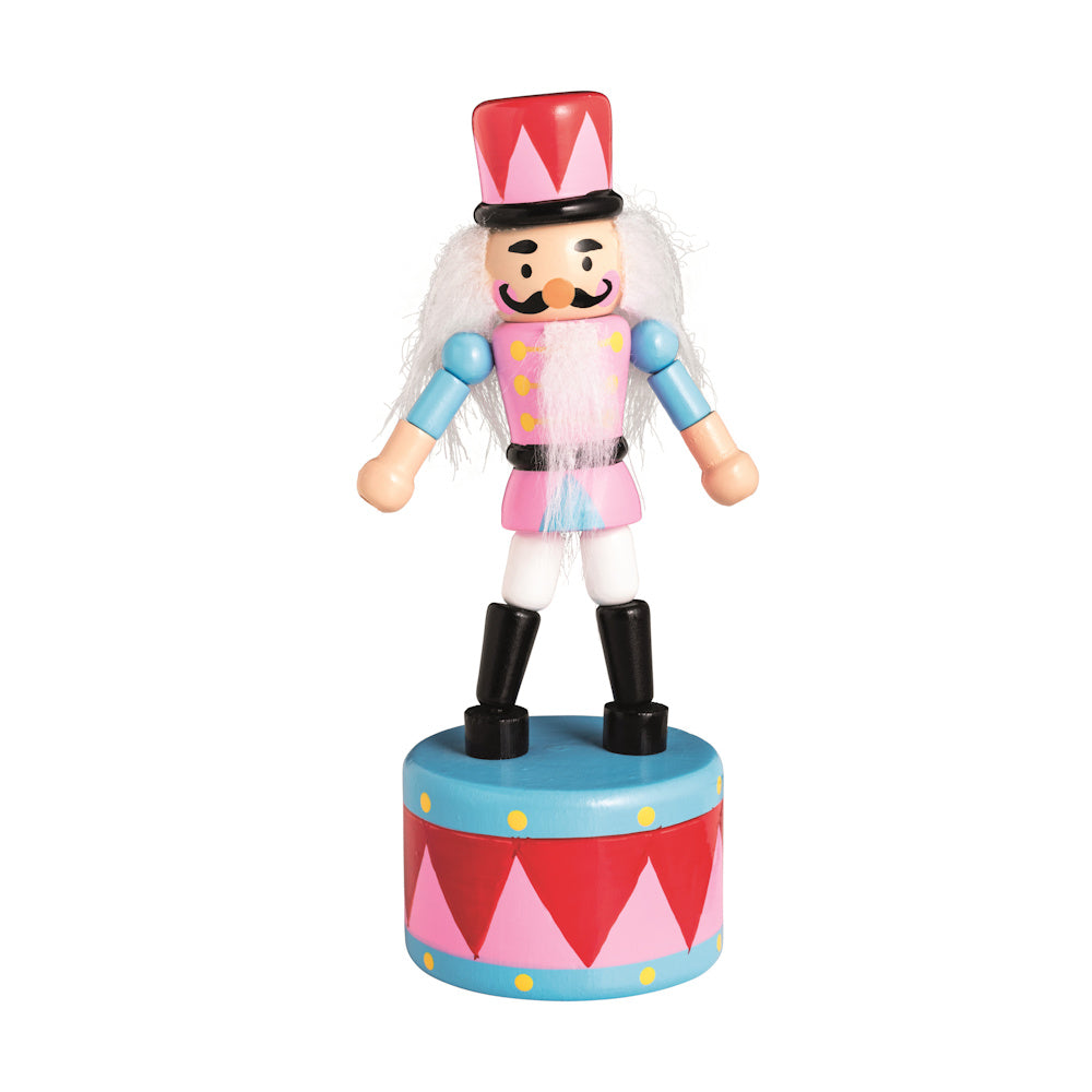 Wooden nutcracker push toy in pink and blue uniform with a tall red hat, standing on a colorful decorative base.