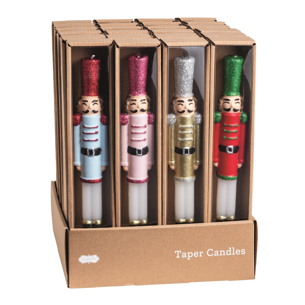 Front view of a cardboard retail display box filled with assorted wax nutcracker taper candles.