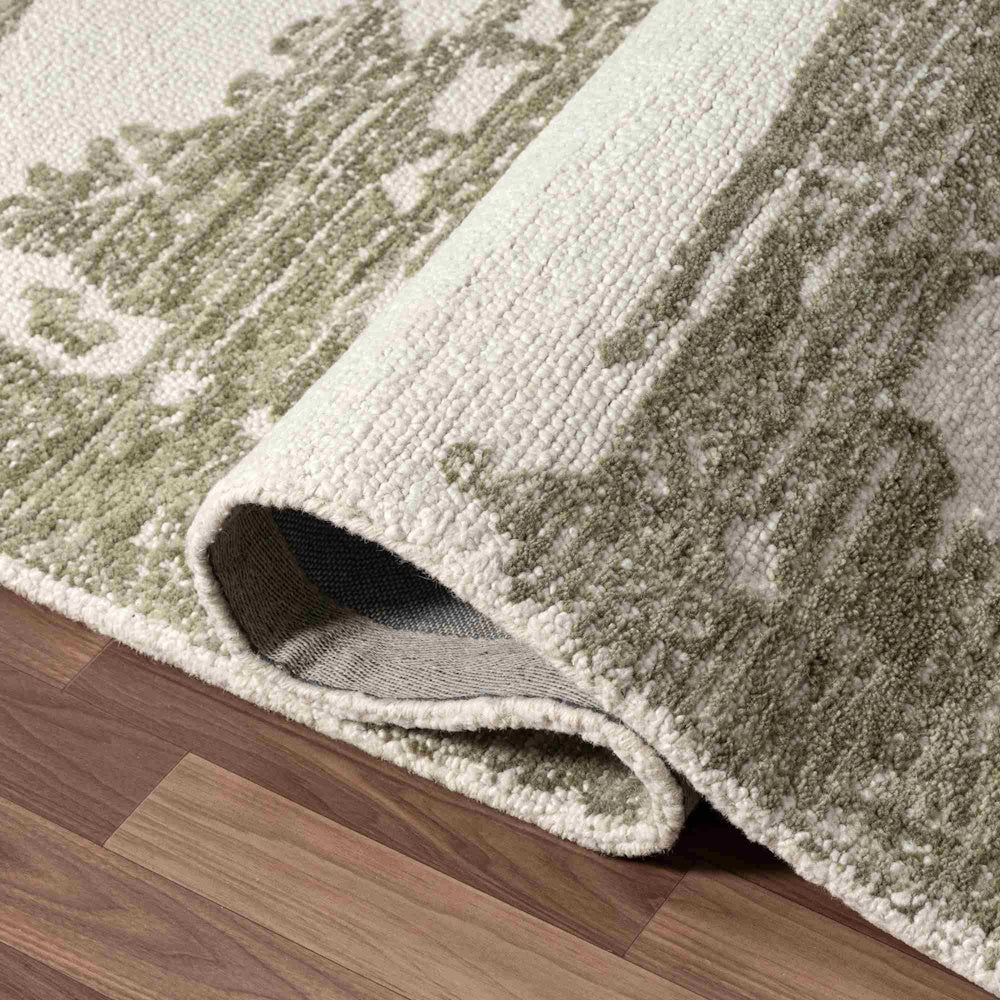 Close-up of a Nuvia hand-tufted rug featuring a green and ivory damask pattern on a dark wood floor.