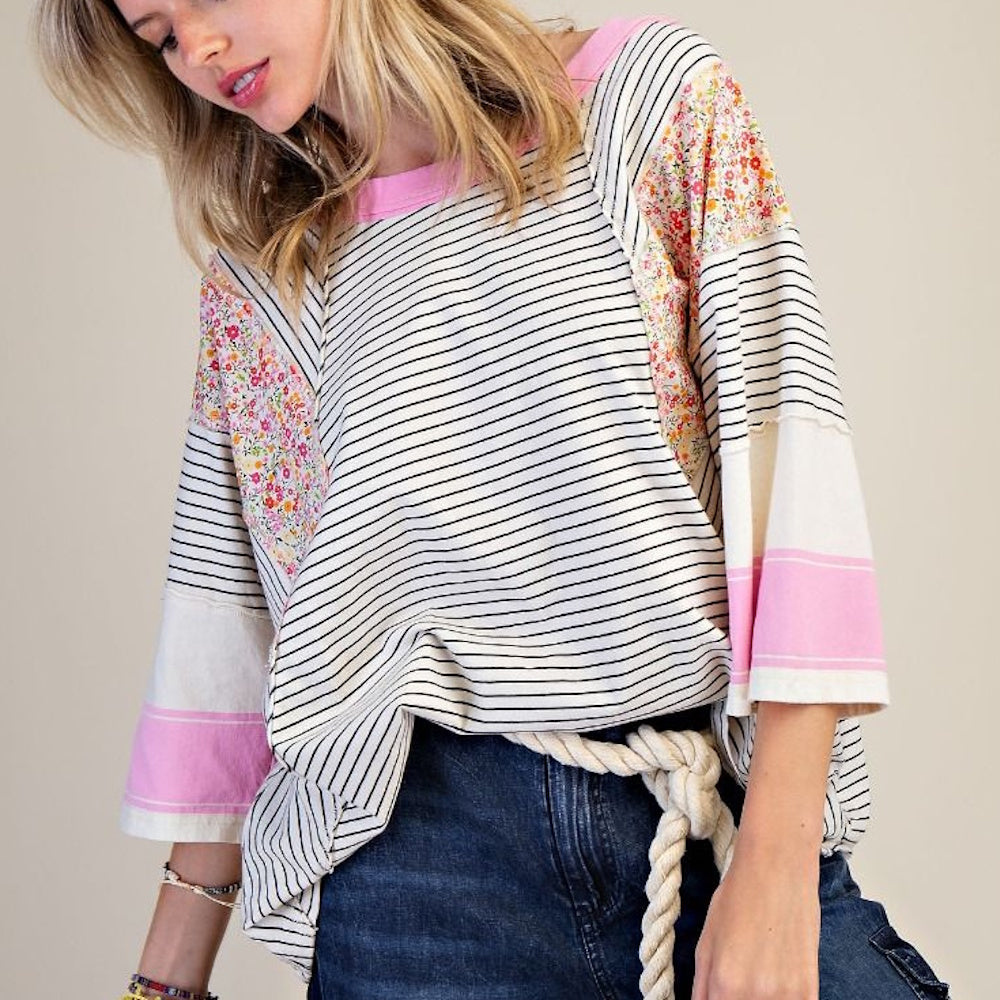 Woman in a striped mineral wash knit top with floral patchwork sleeves, pink accents, and a rope belt over denim.