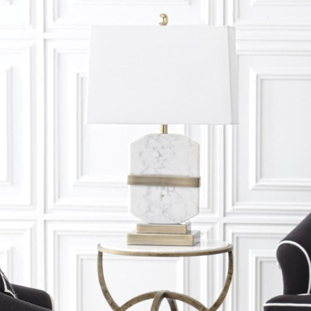 Octagon Arabescato white marble table lamp with brushed gold accents and a white rectangular shade on a side table.