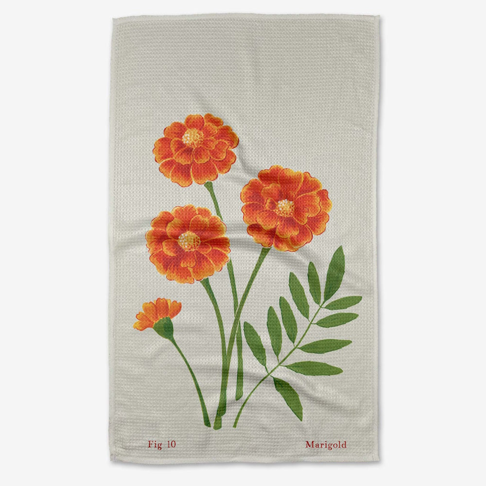 A cream waffle-weave tea towel featuring a botanical illustration of bright orange marigolds.