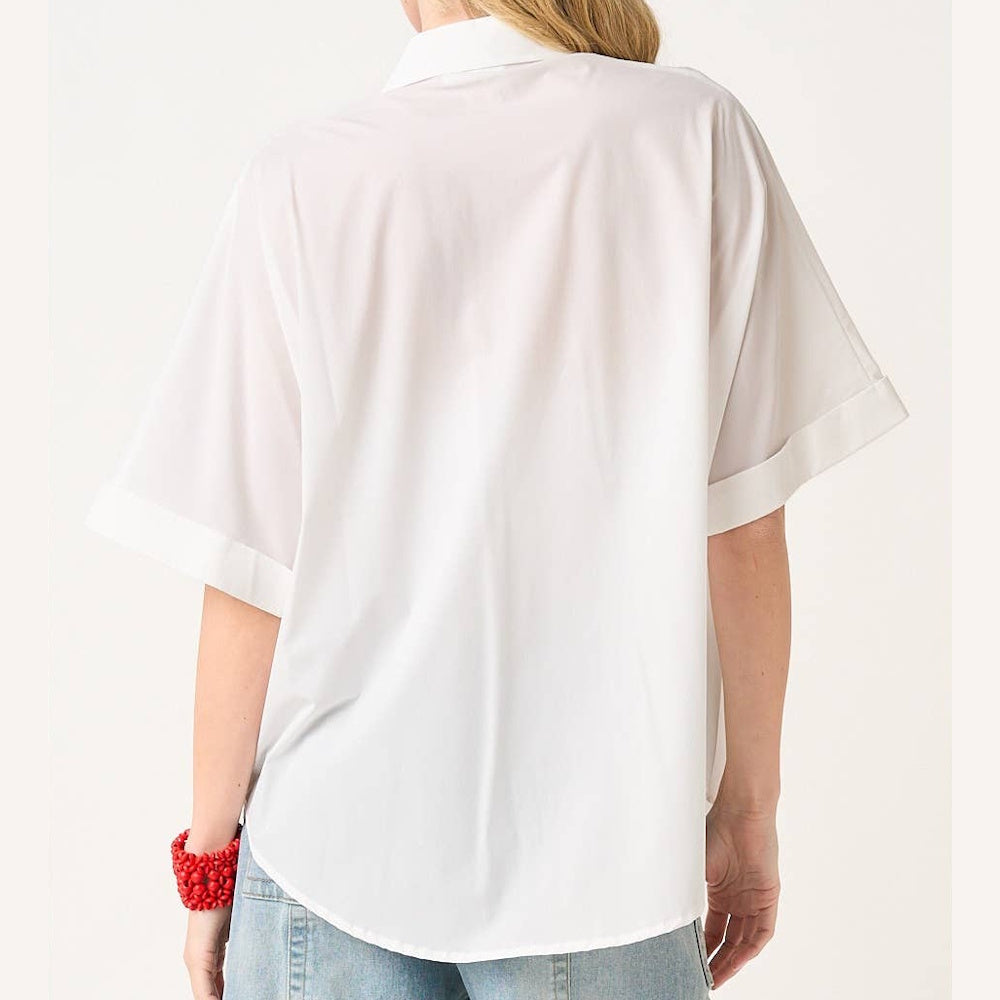Back view of a woman wearing an off-white, soft stretch-woven short sleeve button-down shirt with cuffed sleeves and denim.