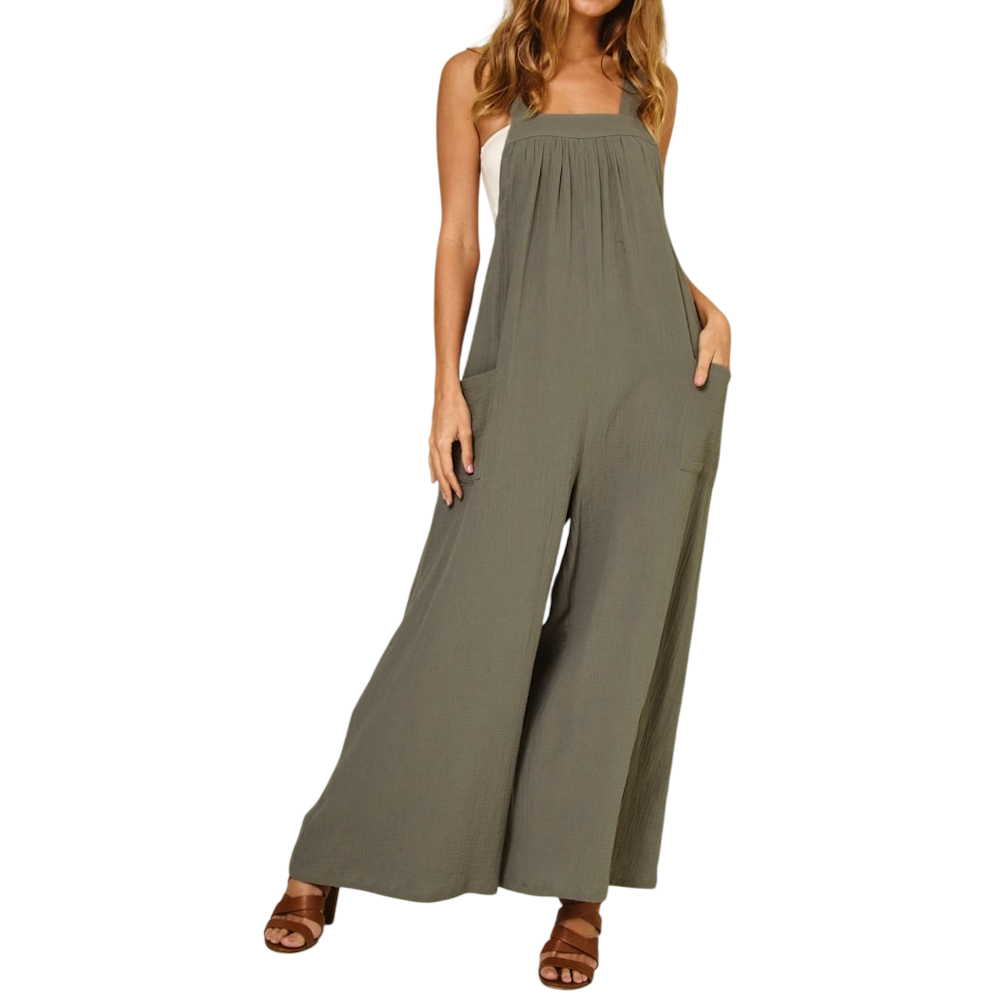 Woman wearing loose, olive green overalls with wide legs, side pockets, and brown strappy sandals.