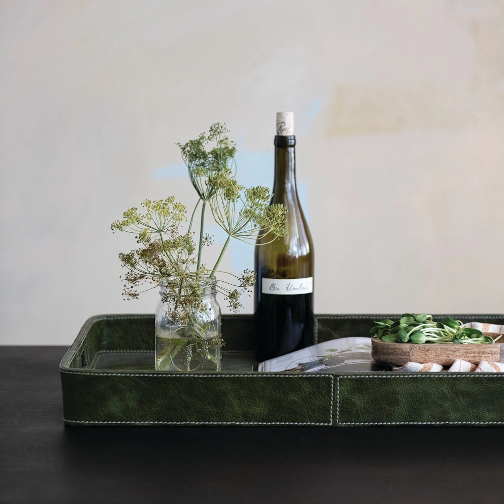Olive green leather decorative tray with handles, featuring a wine bottle and dried flowers for modern home styling.