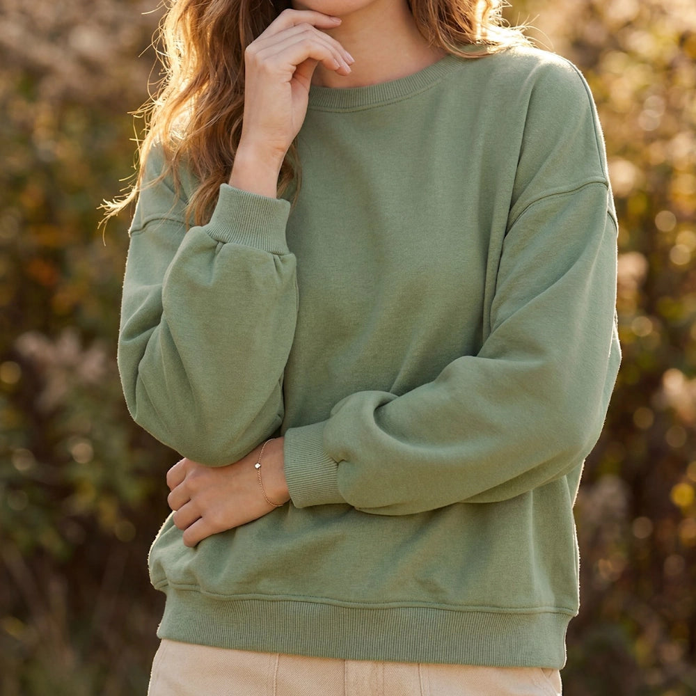 Woman wearing an olive green long-sleeve French terry knit sweatshirt outdoors.