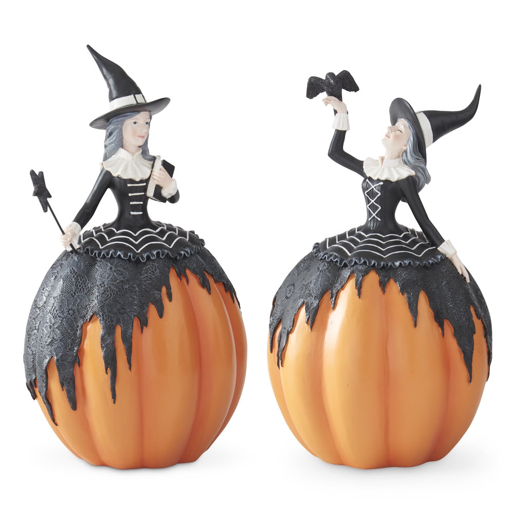Angled side view of two witch figurines with pumpkin lower bodies wearing black dresses.