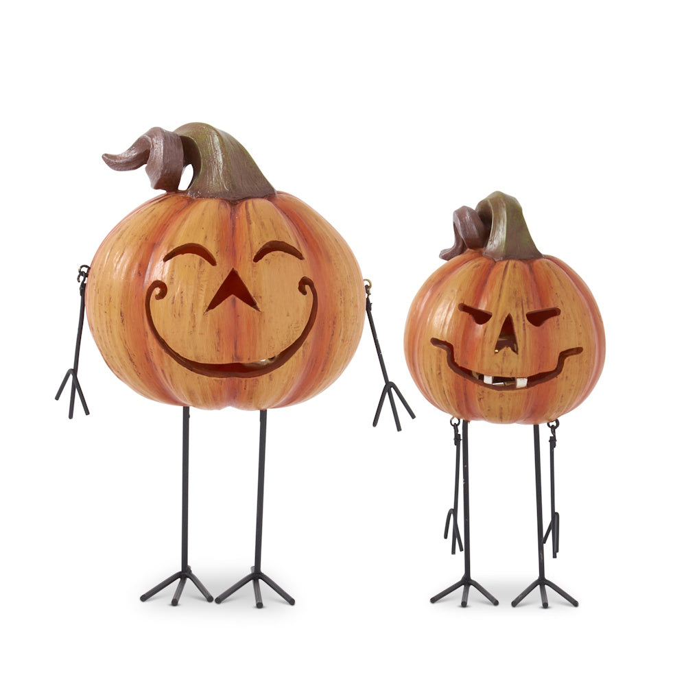 Two decorative Halloween jack-o'-lantern figures with thin, spindly metal legs and arms on a white background.