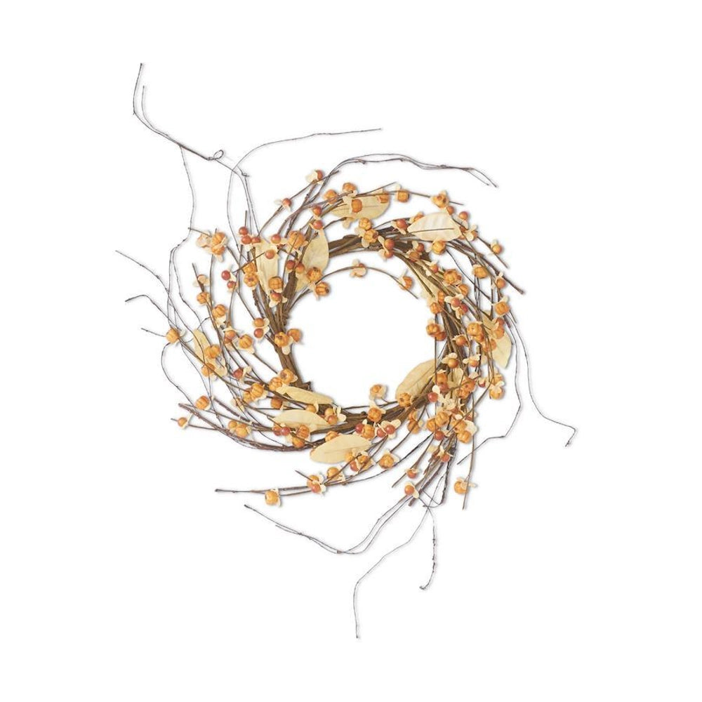 An autumn candle ring made of interwoven brown twigs, decorated with mini orange pumpkins and pale leaves.