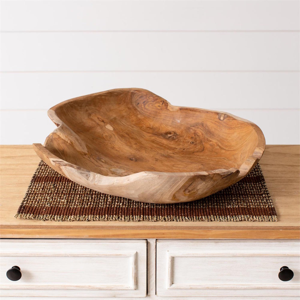 Organic hand-carved teak wood decorative bowl with natural grain on a rustic white sideboard.