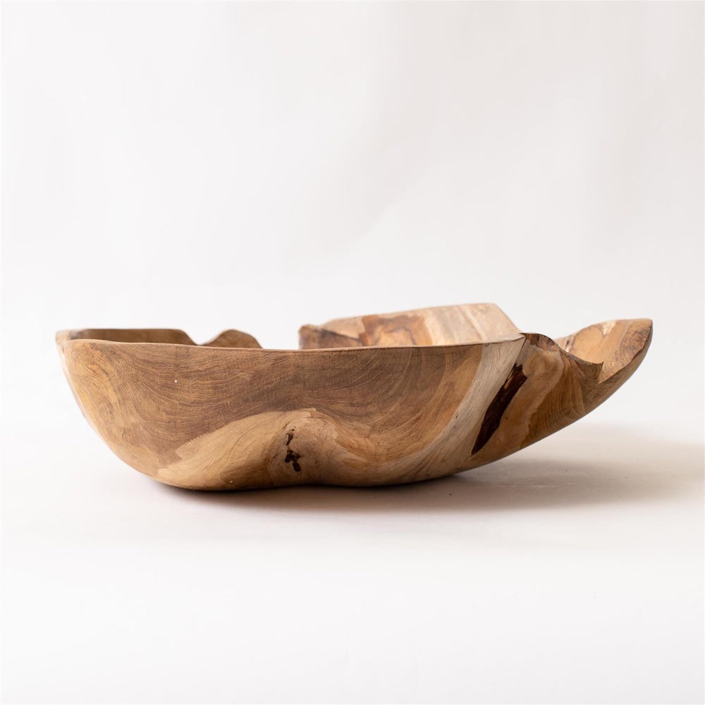 Hand-carved organic shape teak wood bowl with natural grain and live edge, rustic decorative center piece on white background.