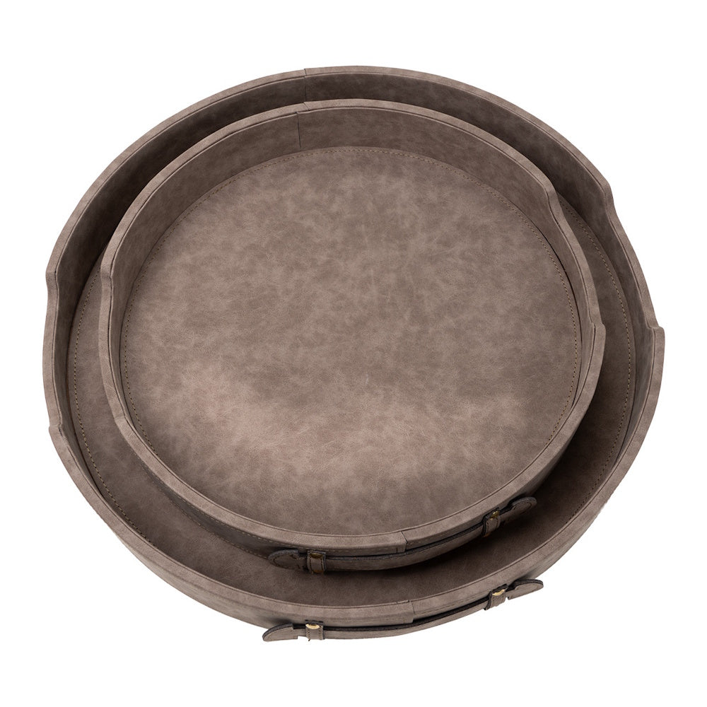 Two nested round faux-leather trays in taupe with side handles and stitching on a white background.