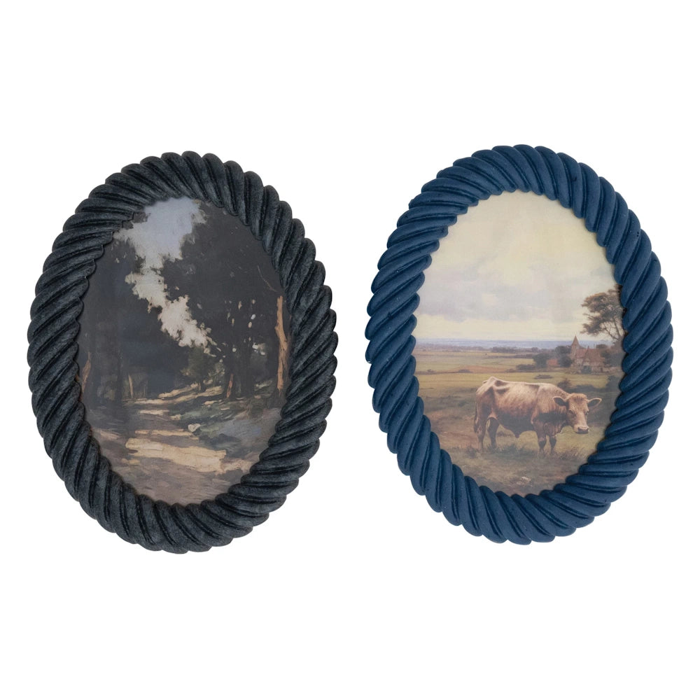 Two oval photo frames with a twisted rope-style texture; one black with a forest print and one blue with a cow in a field.
