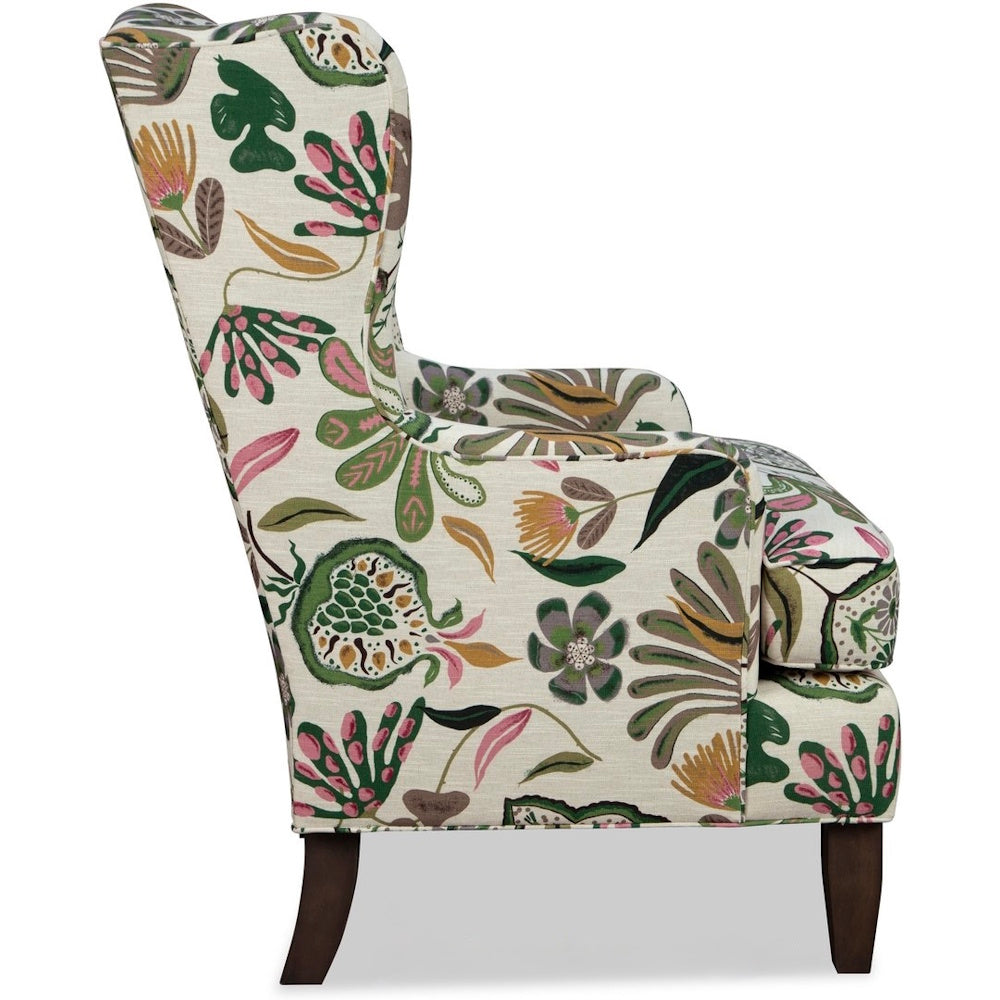Side profile of a wingback armchair with colorful botanical floral pattern upholstery and dark legs.