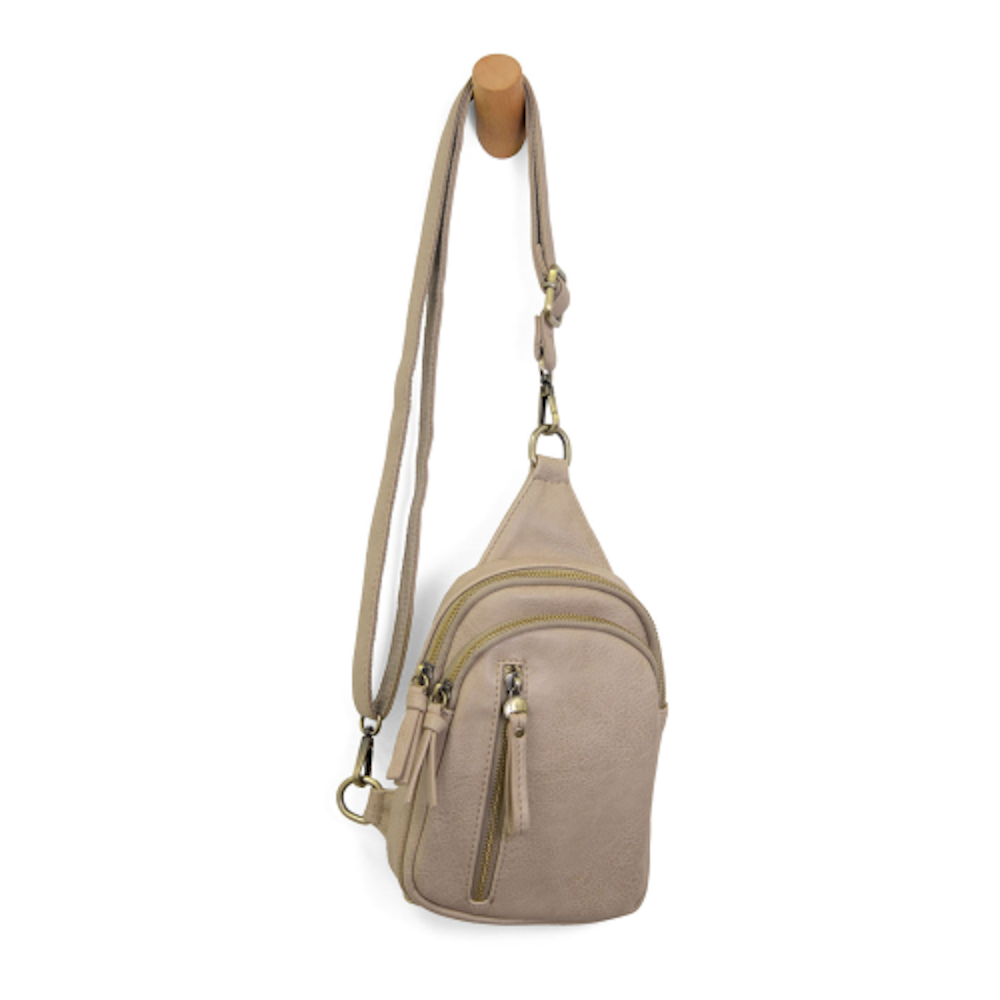 Beige parchment vegan leather sling bag with multiple zippers and adjustable crossbody strap.