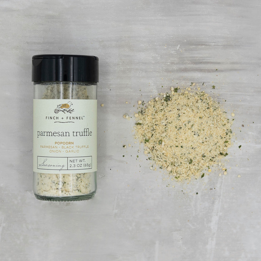 A jar of Finch + Fennel Parmesan Truffle popcorn seasoning next to a small pile of the seasoning.