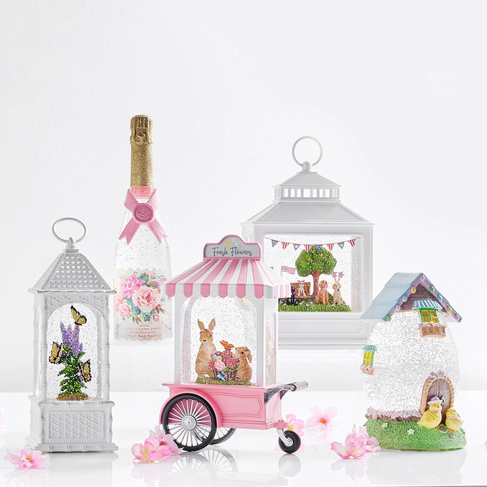 A collection of spring-themed lanterns and decorative items on a white background. Includes pastel colors, butterflies, bunnies, flowers, and soft lighting.