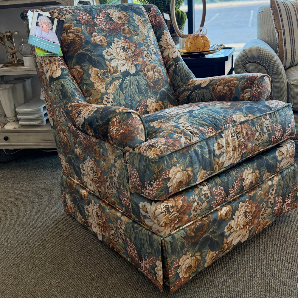 Upholstered swivel glider armchair featuring a rich floral print in teal, cream, and warm brown tones.