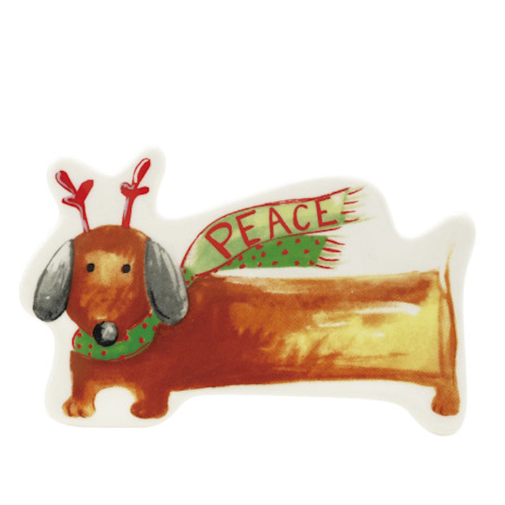 A stoneware dachshund dish wearing reindeer antlers and a green scarf that says "PEACE".