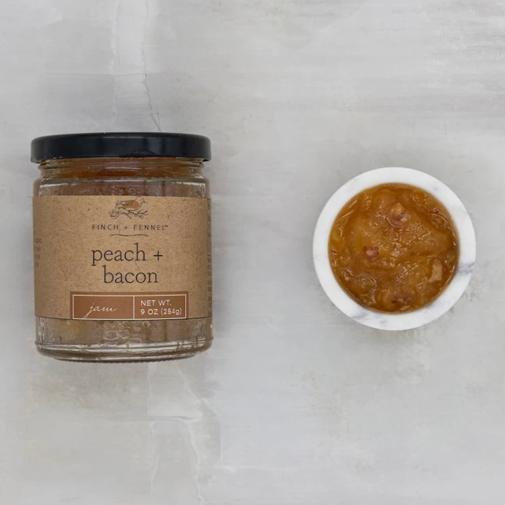 Finch + Fennel Peach + Bacon Jam jar next to a small white marble bowl filled with savory fruit spread.