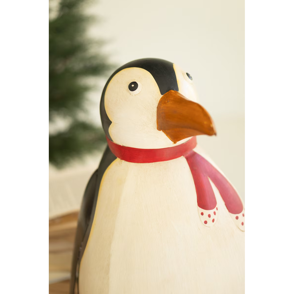 Close-up view of a painted metal penguin sculpture highlighting its head and painted red scarf details.
