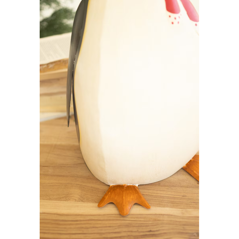 Detailed shot showing base and orange webbed feet of a painted metal penguin sculpture.