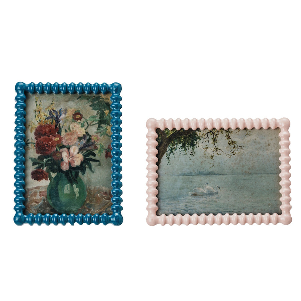 Pair of textured picture frames in blue and pink holding vintage reproduction art prints of flowers and swans.