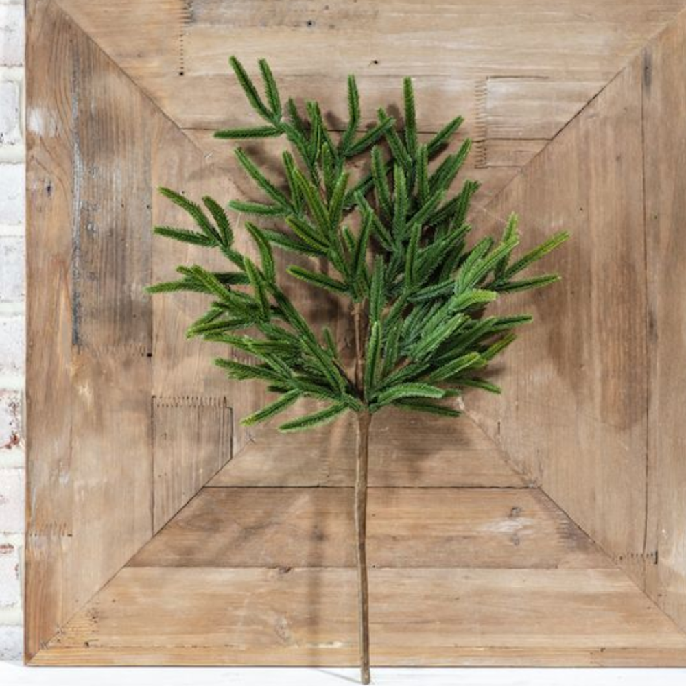 Artificial green pine branch spray displayed against a rustic wooden panel background.