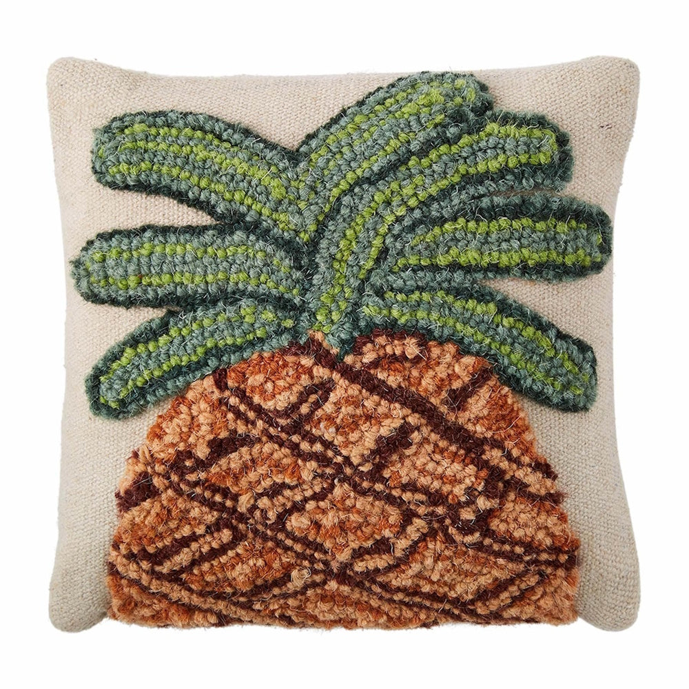 A square, cream-colored throw pillow featuring a textured, hooked-yarn design of a brown and green pineapple.