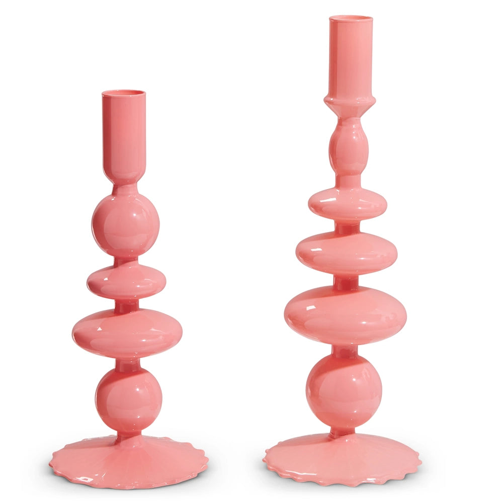 Two pink candlesticks with glossy, smooth surfaces and playful, rounded shapes are displayed against a plain white background, radiating modern elegance.