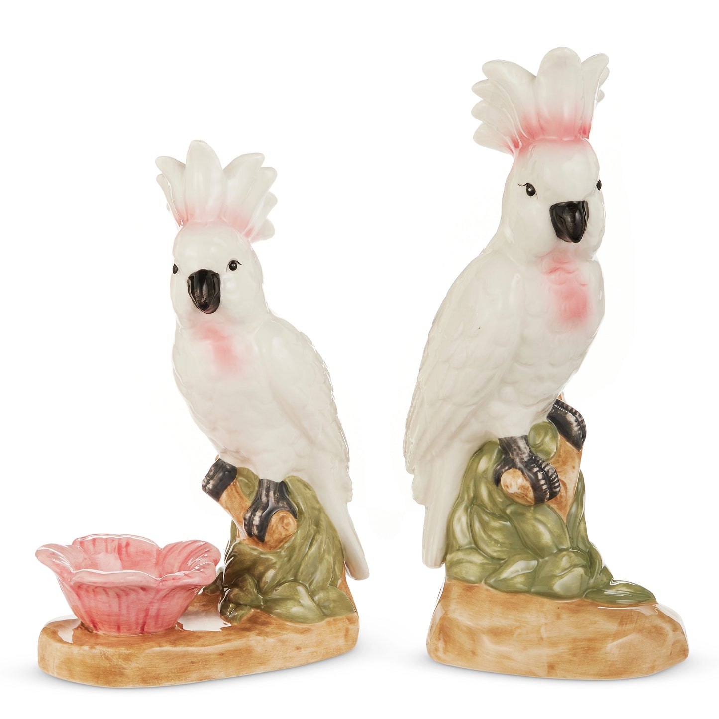 Two porcelain cockatoo figurines with white bodies and pink accents. One stands atop rocks with a pink flower dish, while the other is perched on a leafy base.