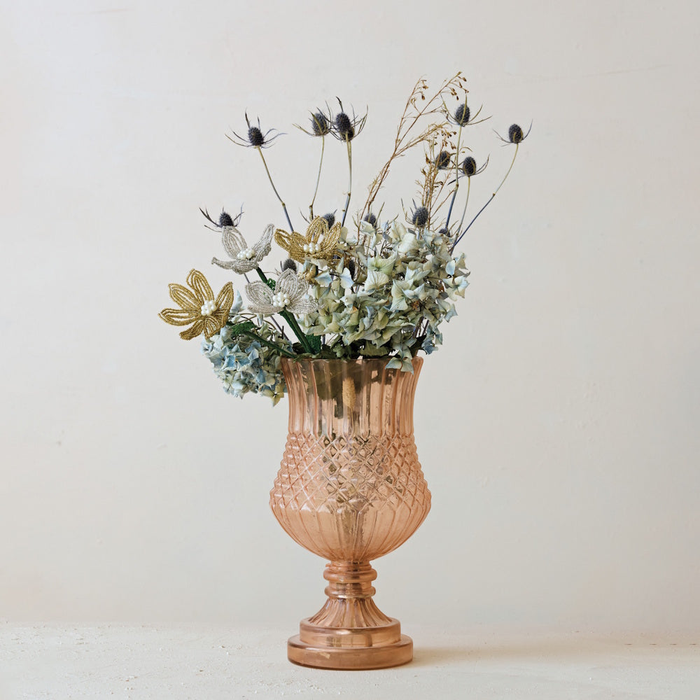 Pink embossed glass footed vase filled with dried flowers, thistles, and beaded floral accents.