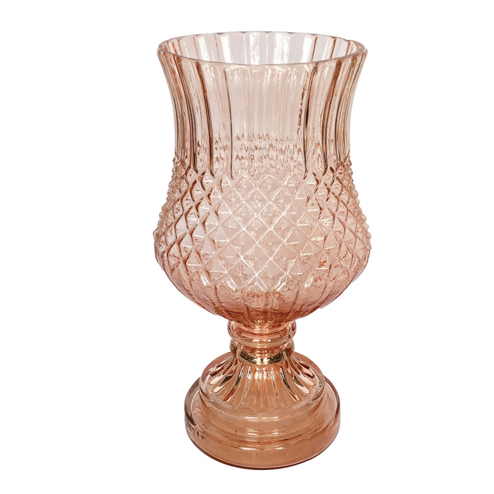 Pink glass footed vase with diamond pattern embossed texture and flared rim on a white background.
