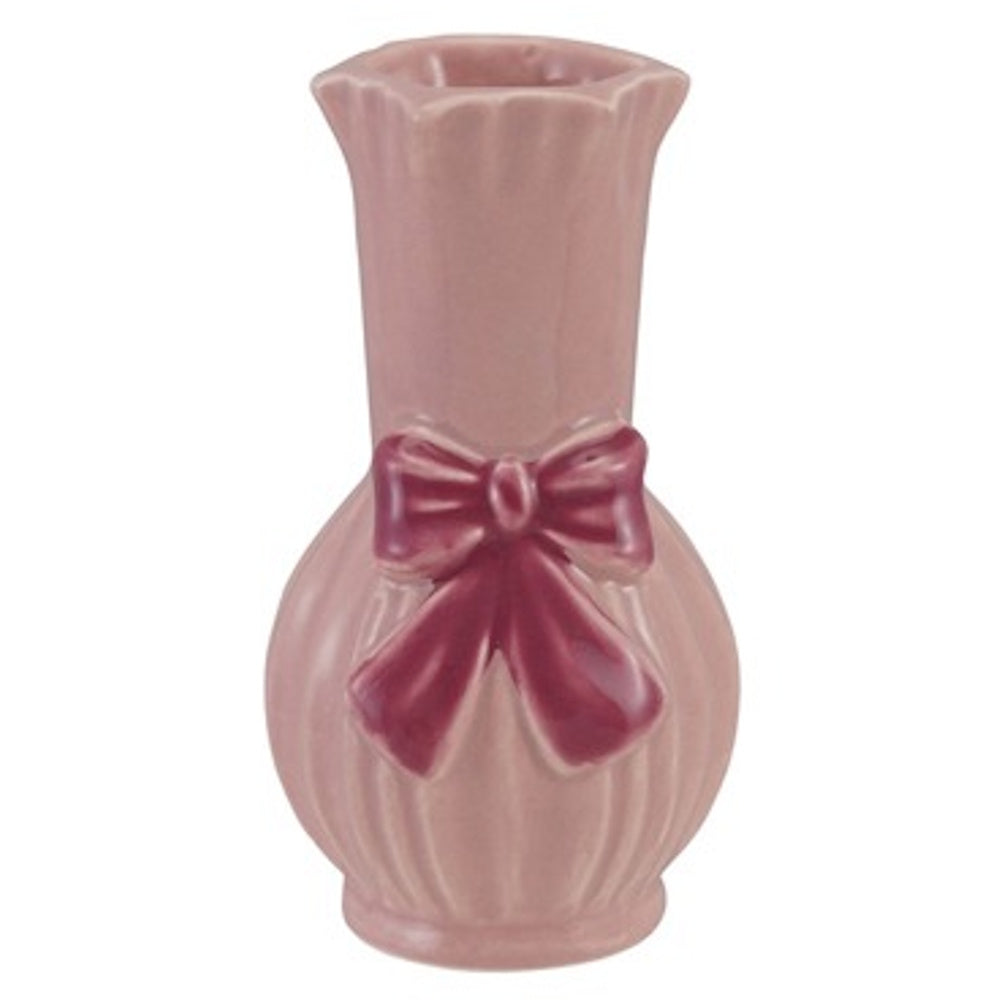A small, light pink fluted ceramic vase with a glossy finish and a dark pink bow sculpted on the front.