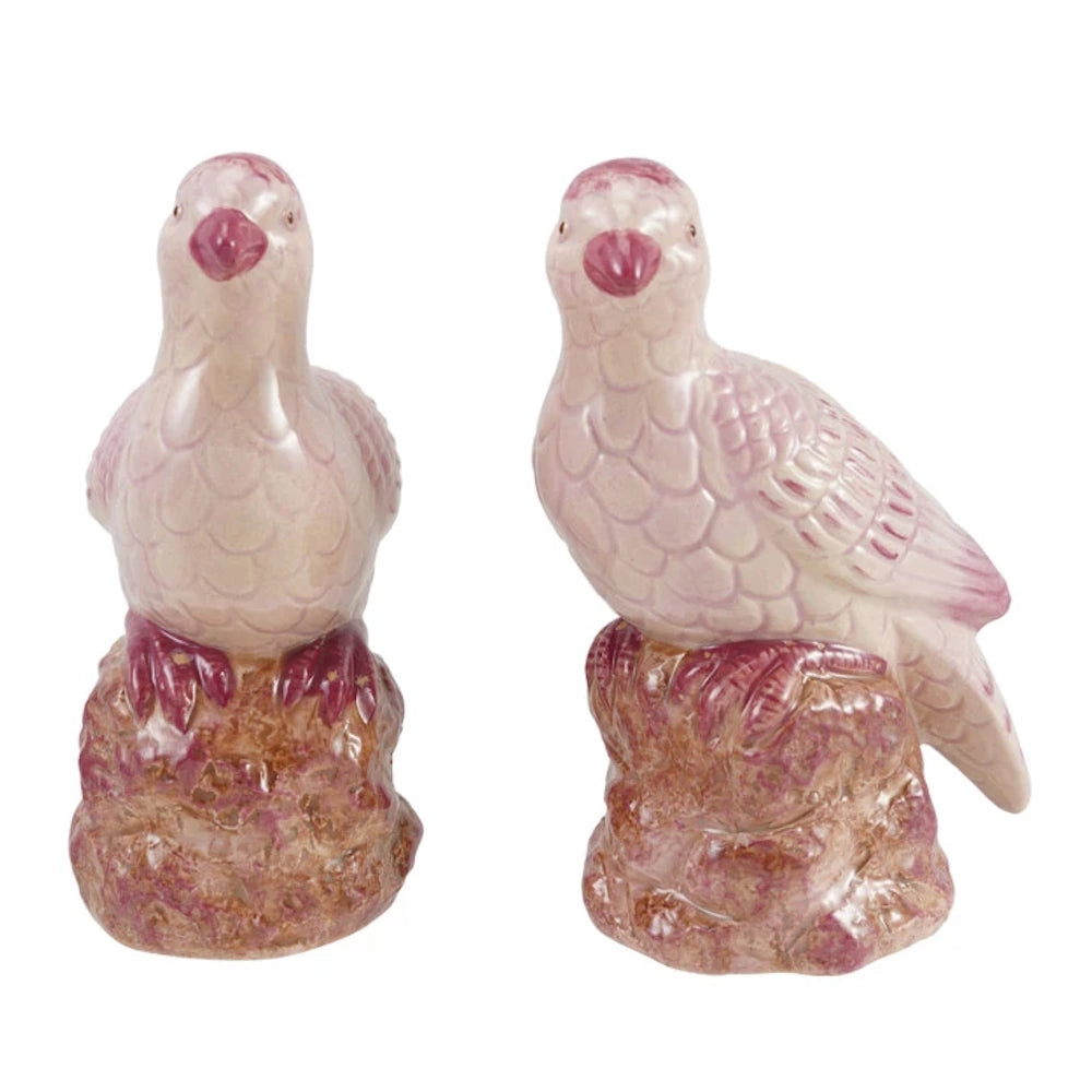 Pair of pink hand-painted stoneware bird figurines perched on brown textured bases, isolated on a white background.