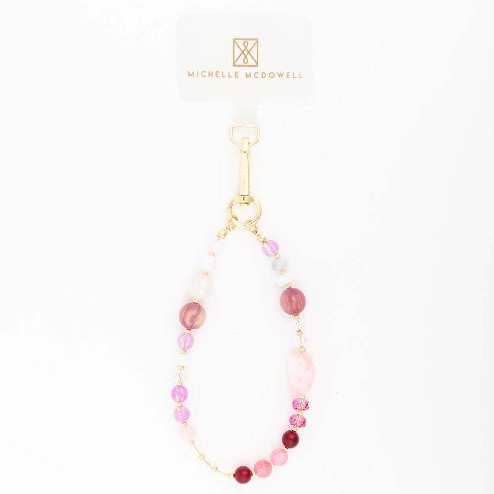 Pink and purple beaded phone charm strap with gold hardware on a plain white background.